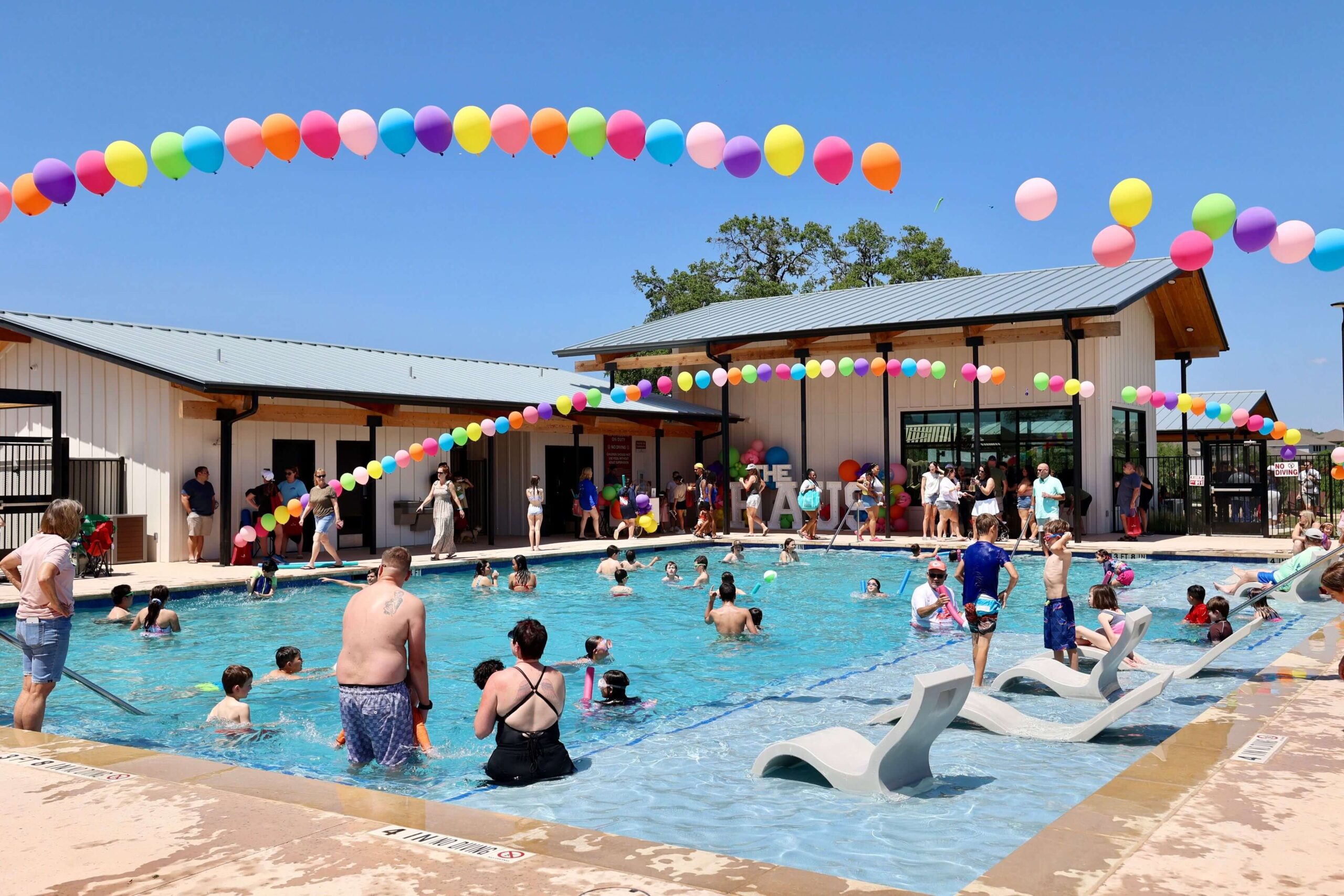 Families playing in the pool with balloons overhead at the Haus grand opening event at Meyer Ranch