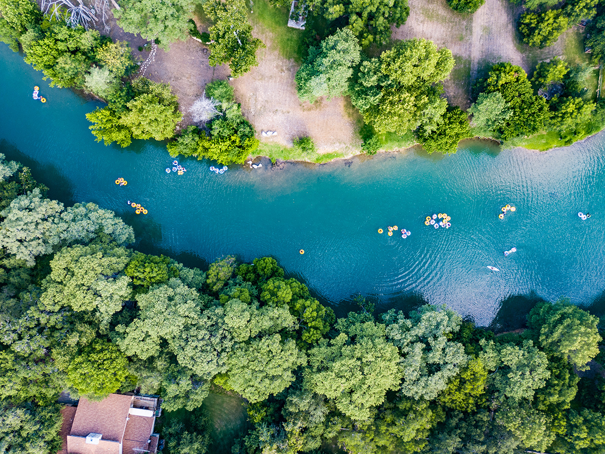 Aerial view of people floating on colorful inner tubes down the Guadalupe River near New Braunfels, TX.