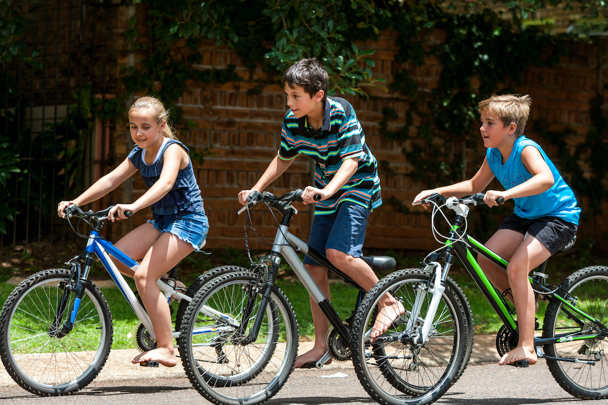 Motion shot of three kids competing with cycles outdoors.